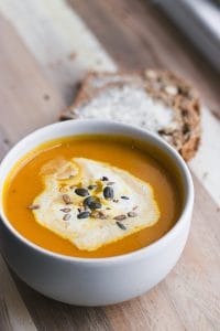 Seasonal soup finished with cream and seeds and served with bread